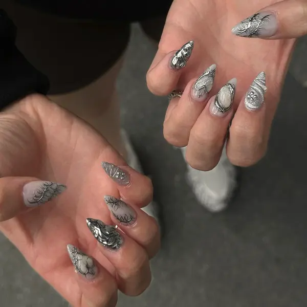 Lange Stiletto-Nägel in Milchweiss mit silbernem 3D-Chrome-Design und Perlenstein